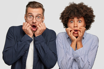 Emotional mixed race couple stare with eyes popped out, keeps jaws dropped, cant believe in awful...