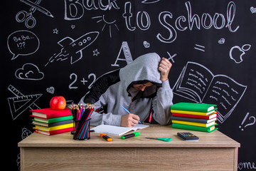 Apathetic and uninterested youngster sitting at the desk with a head leaned on the fists,...