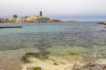 St. Julian's urban skyline with limestone shore in the foreground, at St. Julian's Bay, Malta
