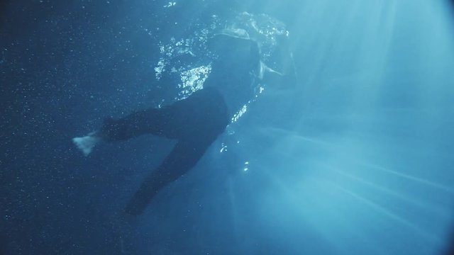 Amazing moving under the water a man dressed trying to get out from the pool and falling down again , dark time outside some lights falls into the water.