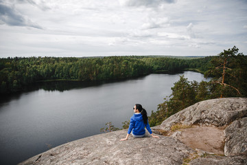 A girl on top of a mountain, in the background of a panorama of mountains and lakes.