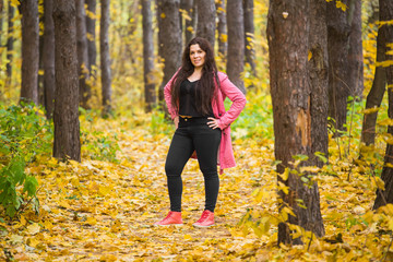 Weather, season, people concept - plus size woman in pink coat over the autumn nature background