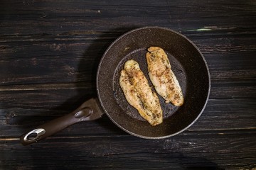 Frying pan with delicious fish on pan wooden background