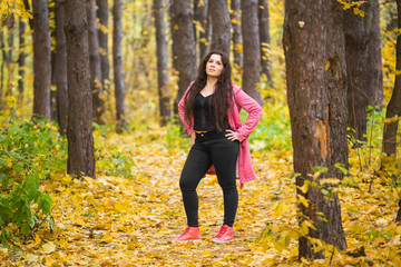 Autumn, nature and people concept - Portrait of plus size woman in pink jacket in park