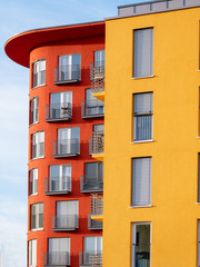 Obraz premium Image of two red and yellow high rise buildings with windows and balconies and blinds