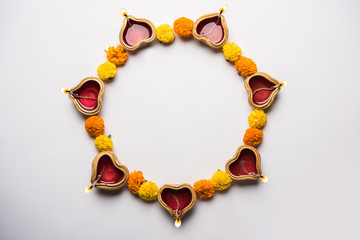 Diwali glowing Diya and flowers arranged in circular shape forming a design with copy space, selective focus