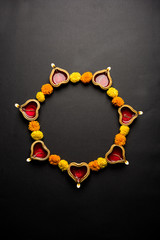 Diwali glowing Diya and flowers arranged in circular shape forming a design with copy space, selective focus