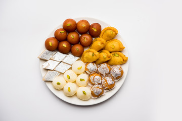 Indian sweets in a plate includes Gulab Jamun, Rasgulla, kaju katli, morichoor / Bundi Laddu, Gujiya or Karanji for diwali celebration