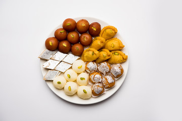 Indian sweets in a plate includes Gulab Jamun, Rasgulla, kaju katli, morichoor / Bundi Laddu, Gujiya or Karanji for diwali celebration