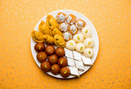 Indian sweets in a plate includes Gulab Jamun, Rasgulla, kaju katli, morichoor / Bundi Laddu, Gujiya or Karanji for diwali celebration