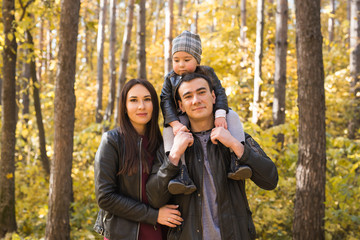 Fototapeta premium People, family and leisure concept - mother, father and little daughter have fun in autumn park