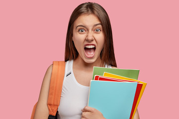 Outraged brunette woman exclaims with fury, keeps mouth widely opened, feels irritated with lazy...