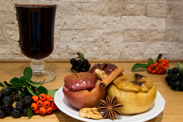 Hot mulled wine with low fat healthy dessert: baked apples with cinnamon and brown sugar, decorated with black ashberry, red and pyracantha.