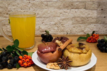 Hot sea-buckthorn healing tea with healthy low fat dessert, baked apples with cinnamon, brown sugar and other spices, decorated with black ashberry and pyrocantha.