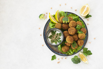 Homemade deep-fried vegetarian  falafel made from ground chickpeas and broccoli,  are laid over a bed of salads .  Middle Eastern food.