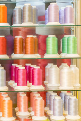 Background with a lot of colorful coils with threads. Bobbins are stacked in three rows, one on the other. The winding is erratic. Multicolored threads BANNER, vertical photo