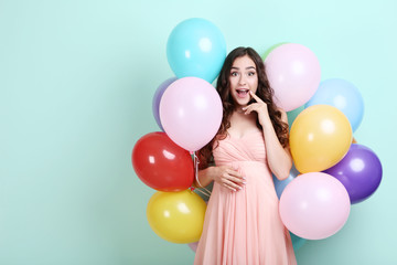 Fototapeta na wymiar Young girl with colored balloons on mint background