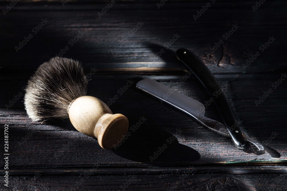 Wall mural Straight razor and shaving brush on a luxury wooden background