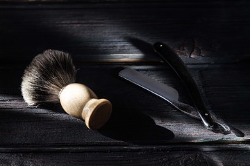 Straight razor and shaving brush on a luxury wooden background
