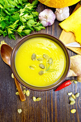 Soup-puree pumpkin with seeds in bowl on wooden board top