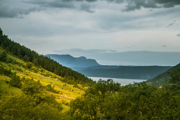 Obraz premium A beautiful autumn landscape of mountains in Folgefonna National park with fjord far in the distance. Fall scenery of southern Norway, Autumn colors in overcast day.