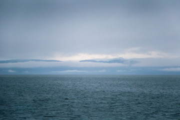 A dramatic, overcast scenery on the coeast of fjord during a ferry ride in Norway near Bergen. Moody autumn landscape of fjord.