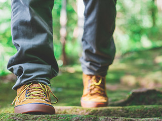 Fototapeta premium Hiking man with trekking boots on the bright green moss passage trail in forest