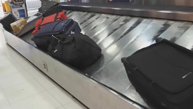 Traveller suitcase baggage on moving conveyor belt at airport arrival 