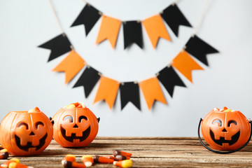 Halloween buckets with candies on grey background