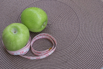 Measuring tape wrapped around a green apple as a symbol of diet.