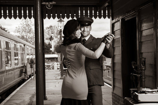 Attractive couple dance on railway station platform with portable record player
