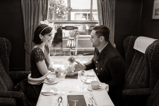 Vintage couple holding hands over table of train carriage
