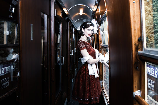 Beautiful woman dressed in red tea vintage tea dress on locomotive train