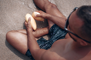 Guy resting on the beach in Thailand in the hands of mango