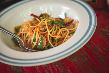 Top view of spaghetti with seafood and thai herb on wooden table