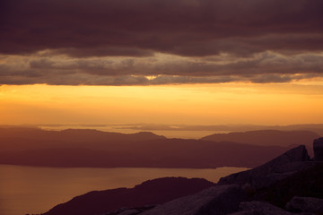 A magnificent sunset scenery over the fjords in Norway in purple tones. Beautiful evening landscape with dramatic sky. Folgefonna national park.