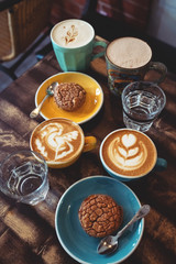 Plate with chocolate cookies and cup of hot coffee on old wooden table. Top view