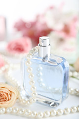 Obraz na płótnie Canvas Perfume bottle with rose flower and beads on white background