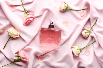 Perfume bottle with flowers on satin background