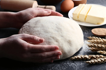 Female hands holding raw dough on black wooden table