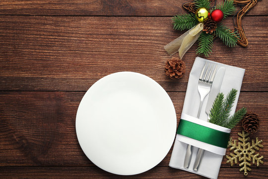 Kitchen cutlery with white plate and christmas decorations on wooden table
