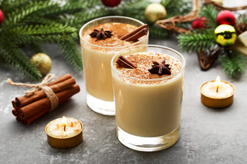 Eggnog in glasses with cinamon and star anise on wooden table