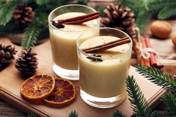 Eggnog in glasses with cinamon and star anise on wooden table
