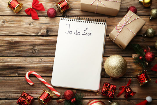 To do list in notepad with christmas decorations on wooden table