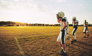Young American football players walking off a field after practi