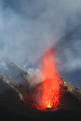 Esplosione Stromboliana di lava incandescente al cratere del Vulcano Stromboli in eruzione con sfondo mare
