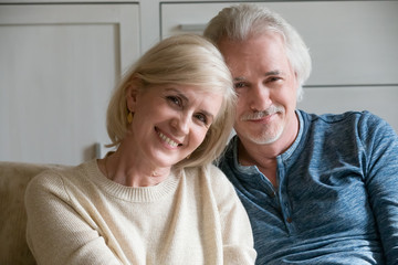 Headshot portrait of smiling loving mature old man and woman dating feeling happy together, middle aged senior retired romantic couple family embracing looking at camera bonding posing at home