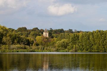 Fototapeta na wymiar Landscape view over Whittlingham Lake in Norfolk, with old church rising out of the woods.