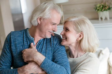 Caring loving senior old man admiring middle aged woman enjoying sincere feelings for many long years in happy marriage, romantic elderly mature smiling family couple looking at each other embracing