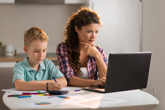 Mother Working On Laptop While Being With Her Son At Home